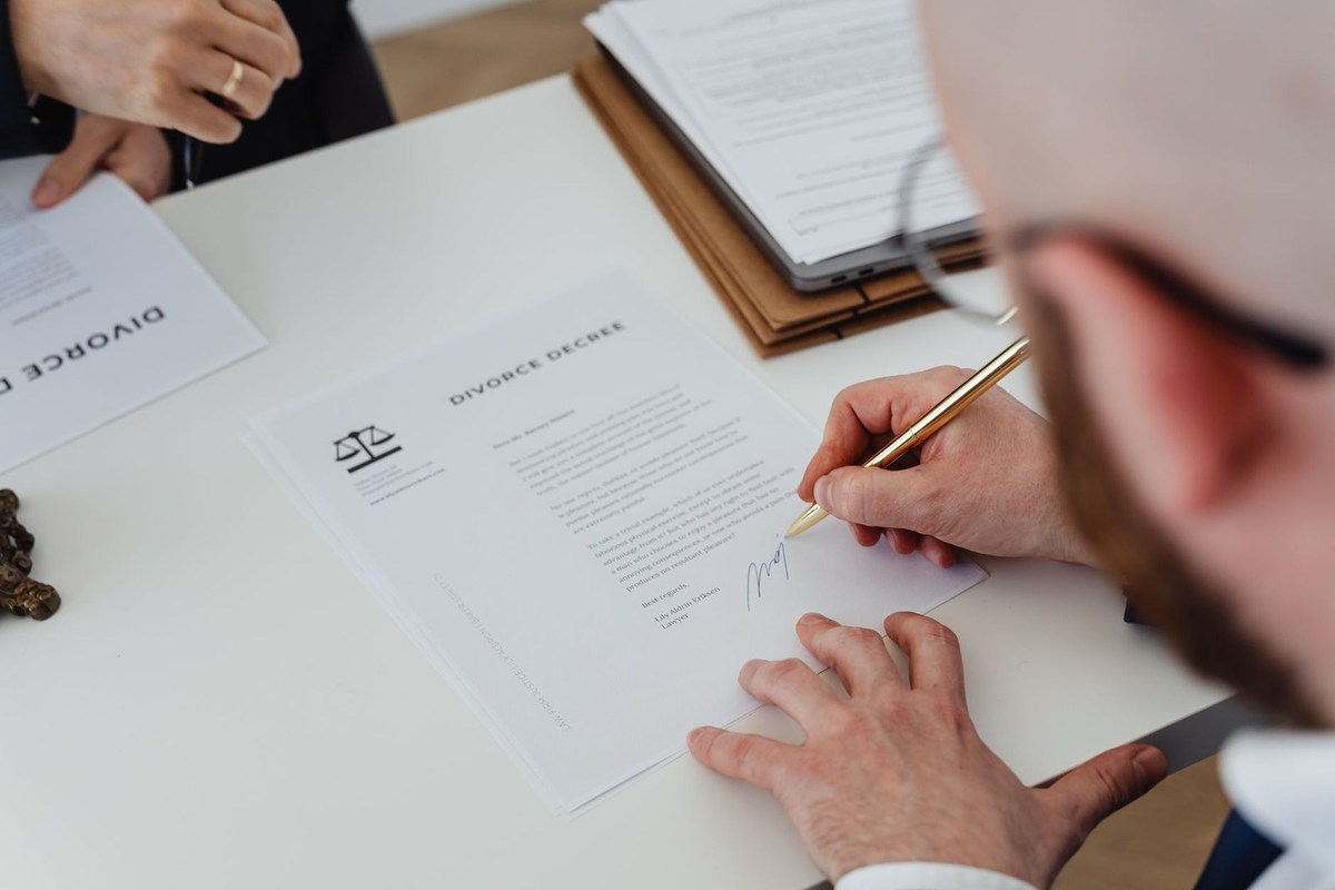 Homme en train de signer un document à une table de bureau