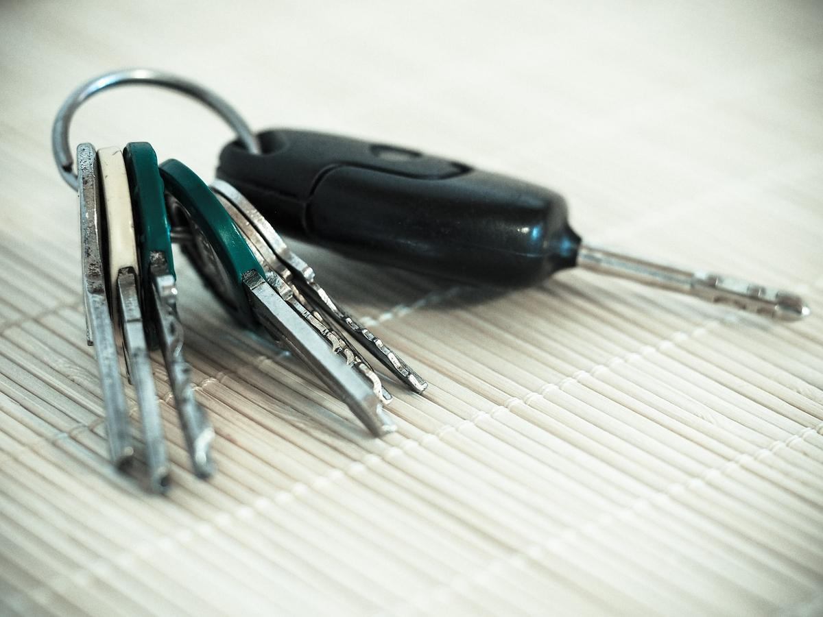 Clés de voiture et maison sur un tapis de bambou, une clé en plastique Clés de voiture et maison sur un tapis de bambou, une clé en plastique